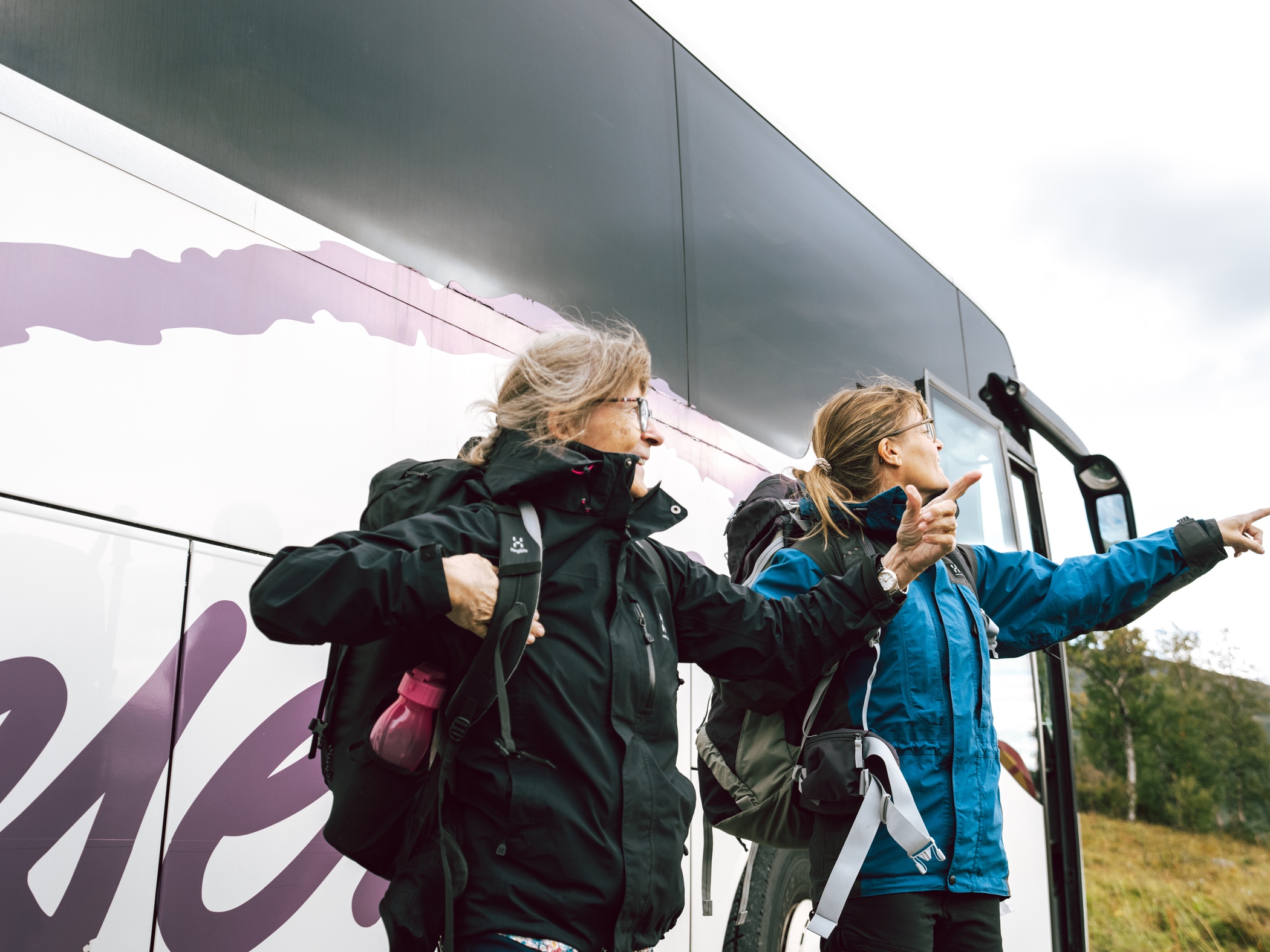 En grupp människor väntar vid en hållplats för att stiga på en gul buss.