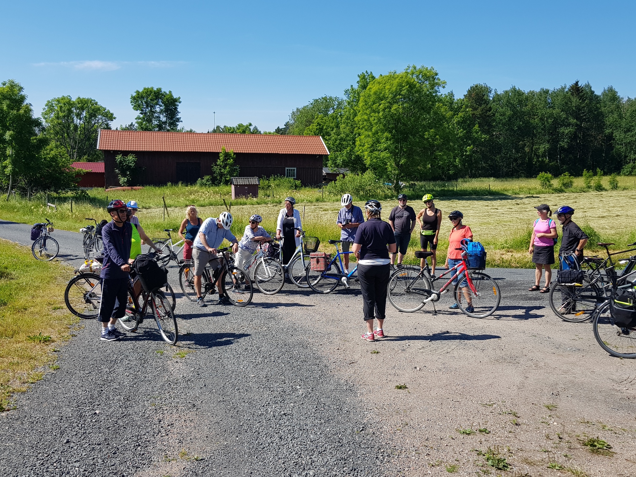 En grupp cyklister står samlade vid en vägkorsning på landsbygden under en paus. 