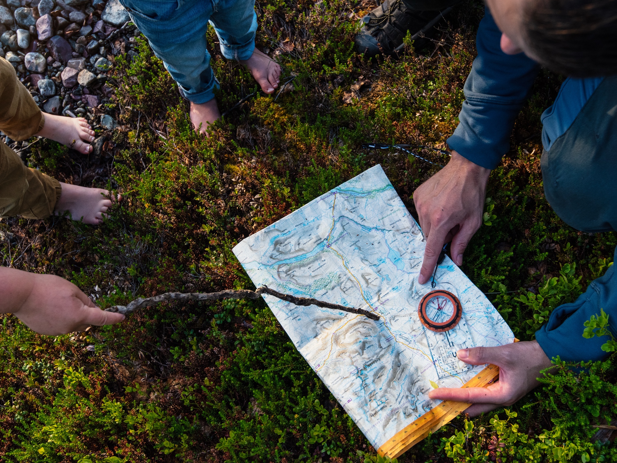 Personer tittar på en karta med kompass utlagd på marken.