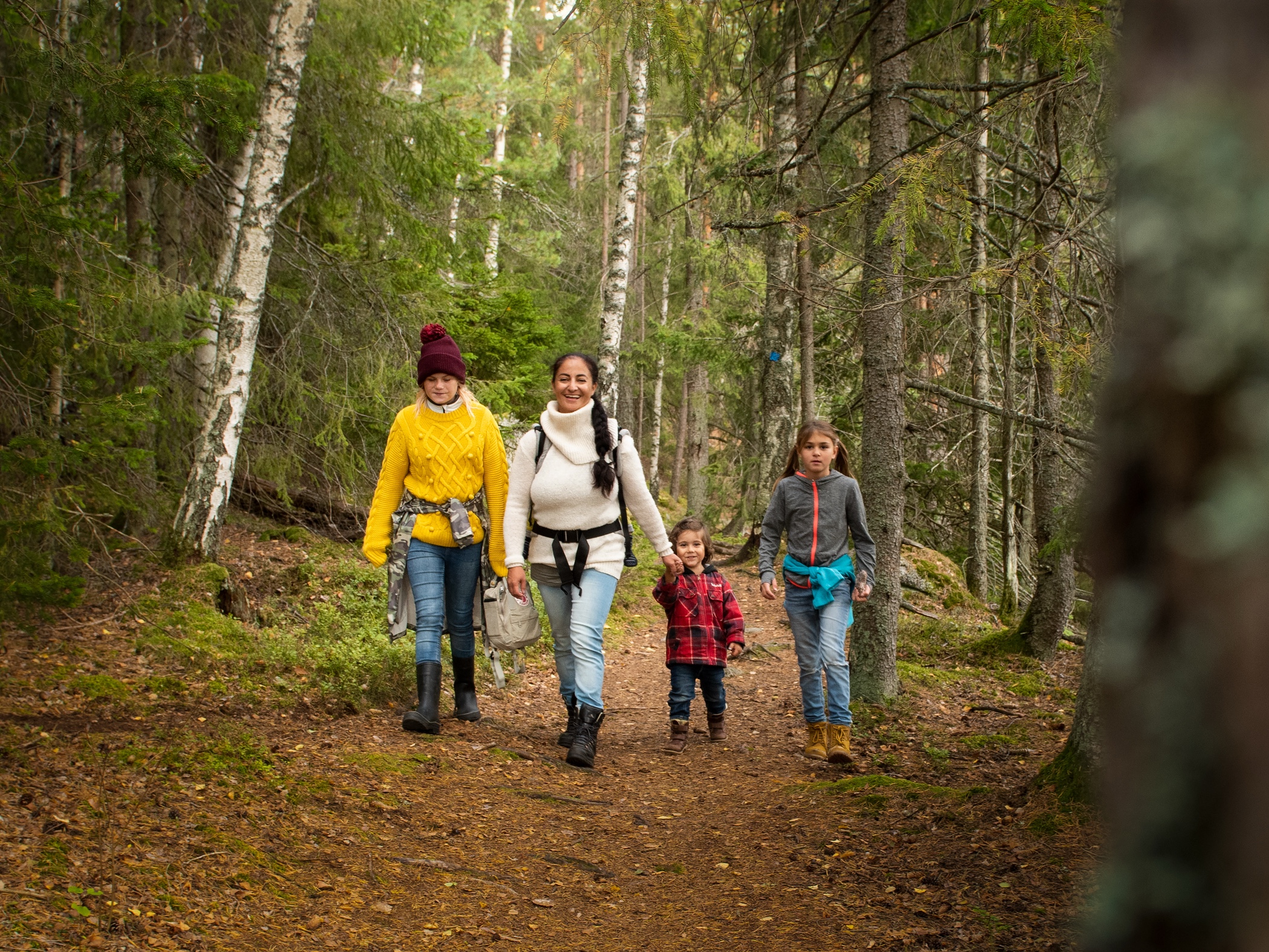 En familj vandrar längs en skogsstig under hösten.