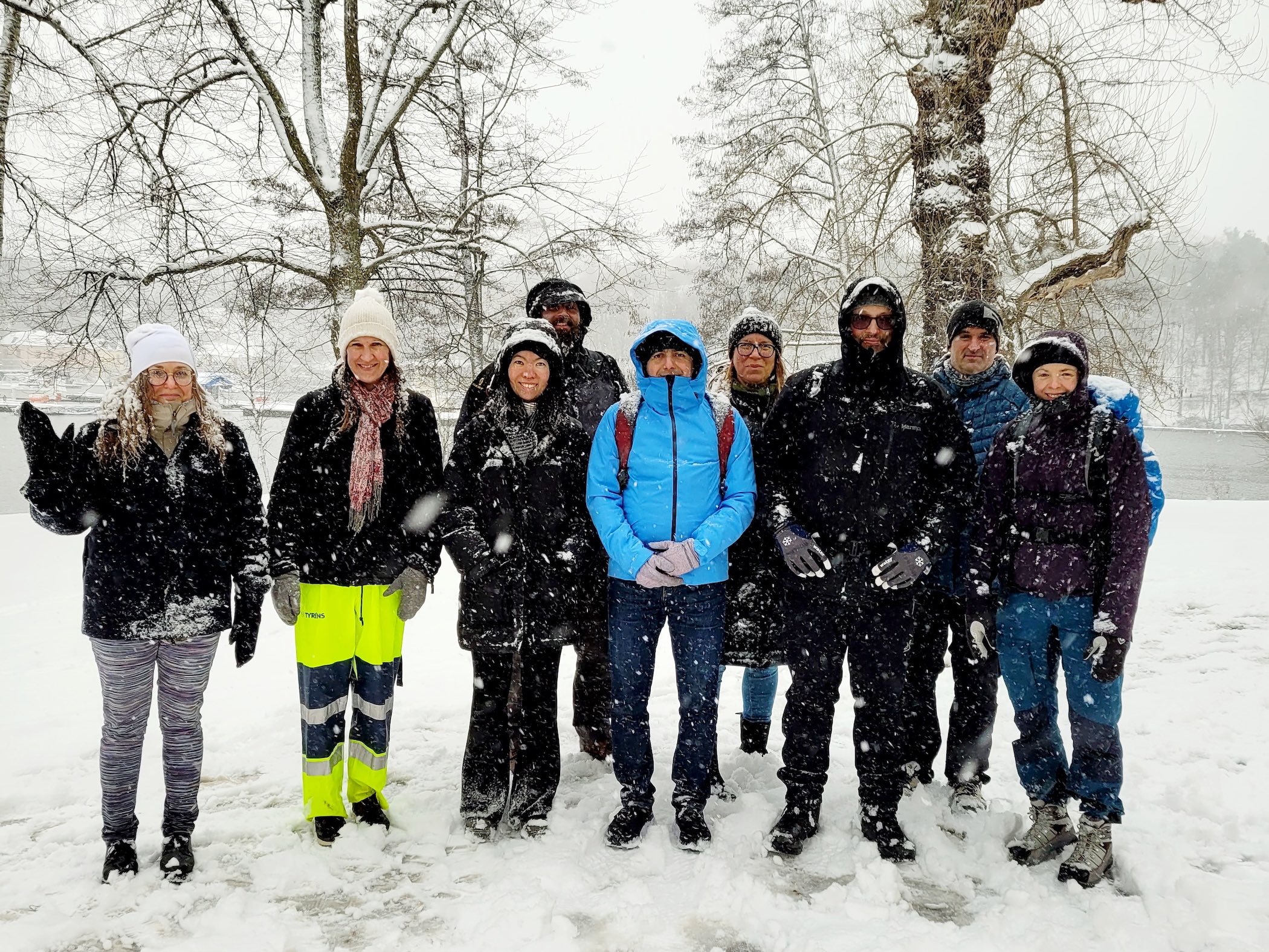 Grupp personer står utomhus i snöfall under vinterutflykt.