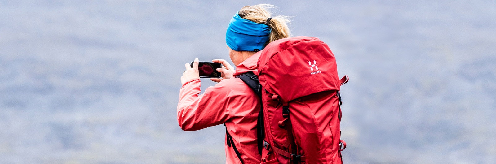 Rödklädd vandrare fotograferar landskapet