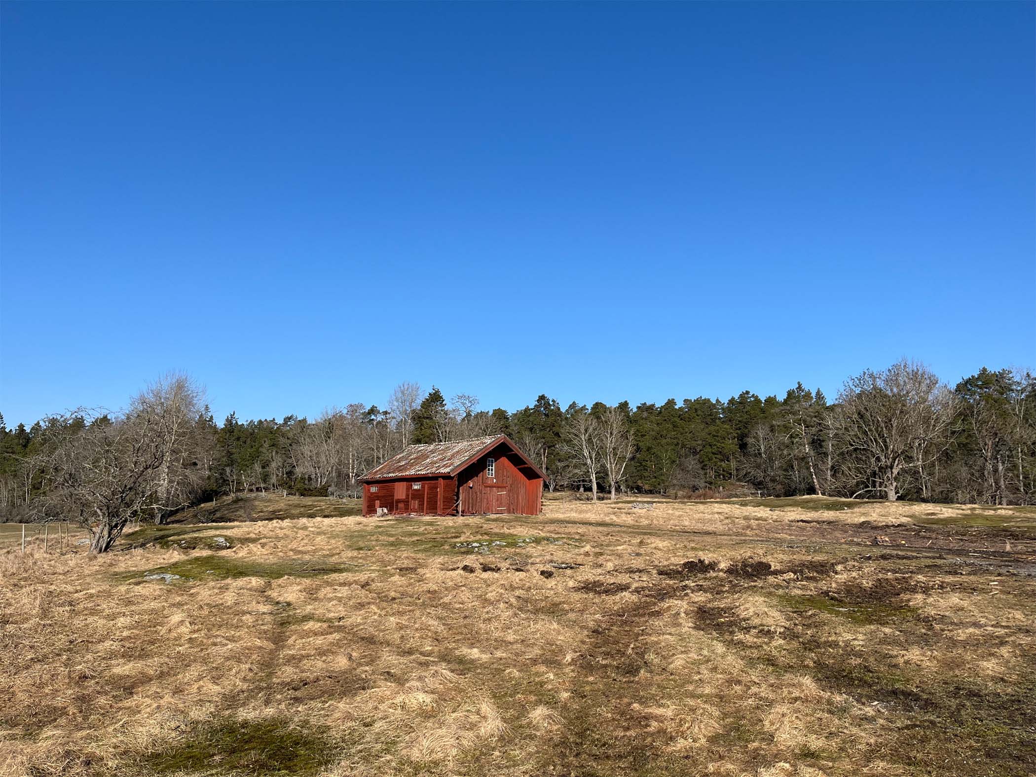 Rött hus på en åker i solen i Erstavik, Stockholm.