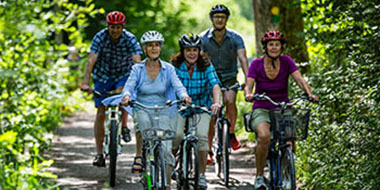 Grupp med personer cyklar på skogsväg