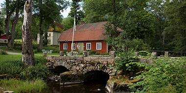 STF Årås, en röd byggnad vid vattnet och en stenbro.