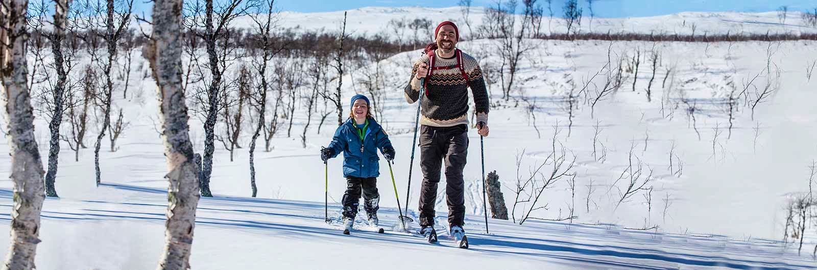 pappa och son som skidar på fjället