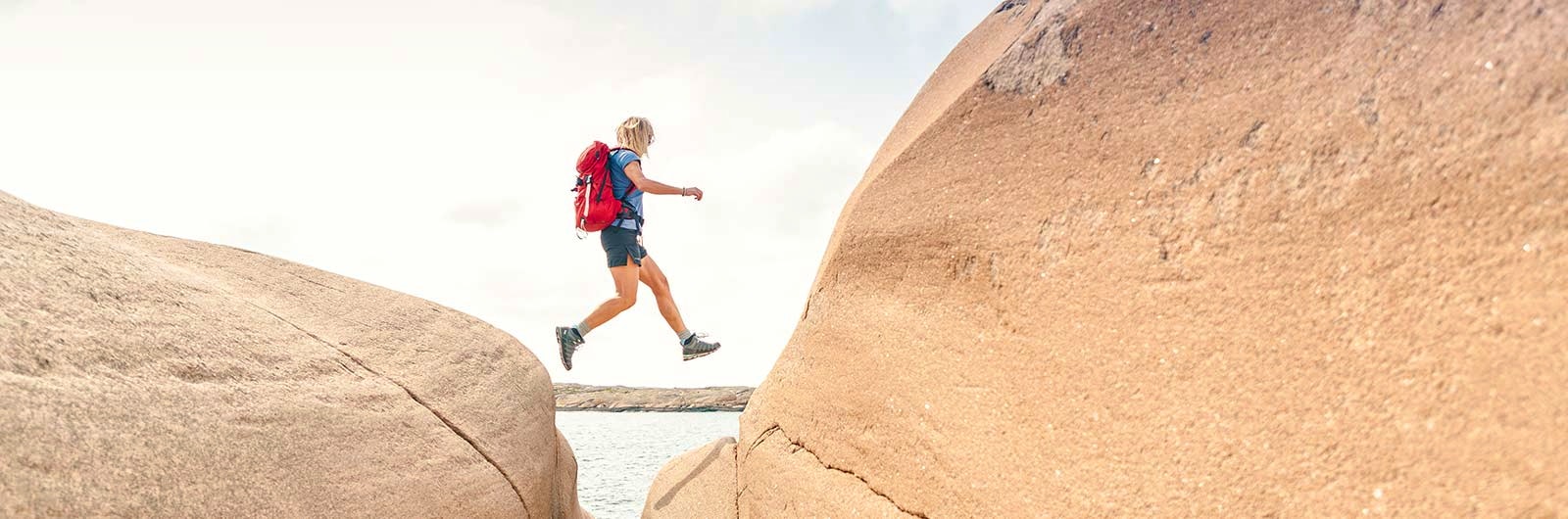 Vandrare hoppar mellan klippor på Bohusläns kust