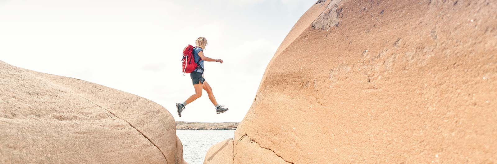 Vandrare hoppar mellan klippor på Bohusläns kust