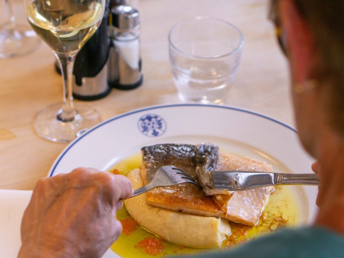 STF Kebnekaise Fjällstation tallrik med fisk och ett glas vin. 