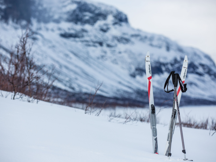 Ett par turskidor nerstuckna i snön framför en bergvägg. 