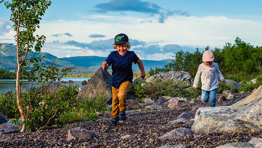 Två barn springer och leker i naturen