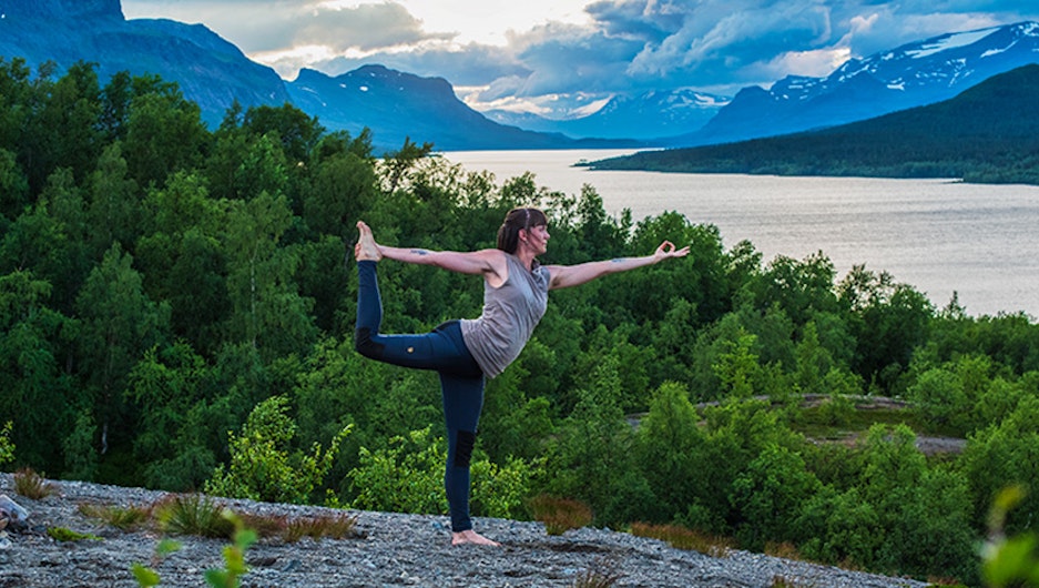 Kvinna yogar med fjällutsikt bakom sig