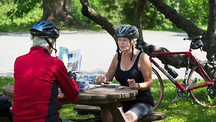 Äldre par sitter vid bord och läser i cykelguide.
