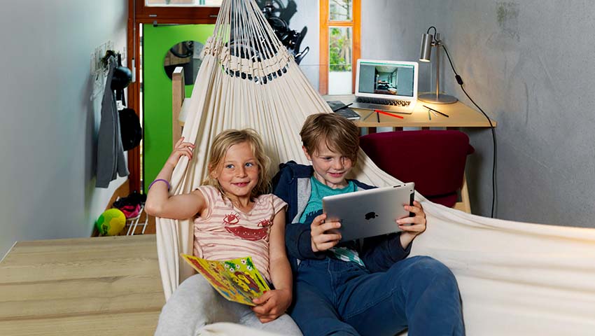 Två barn ligger och läser i hängmatta på Ohboy Hotell i Malmö
