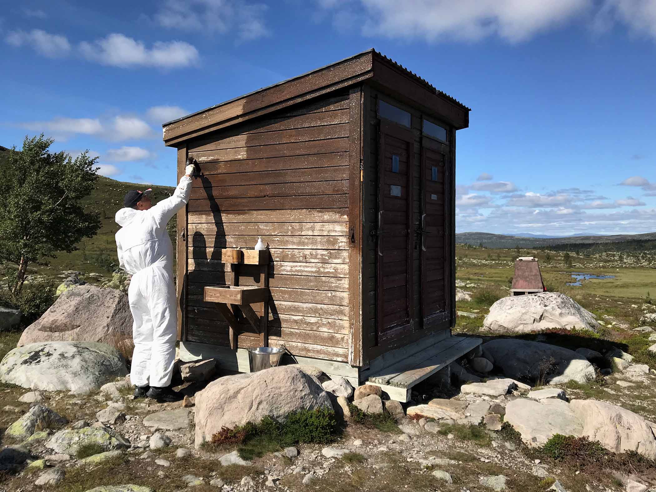 Ideell dugnadsarbetare målar om ett dass i fjällen. 