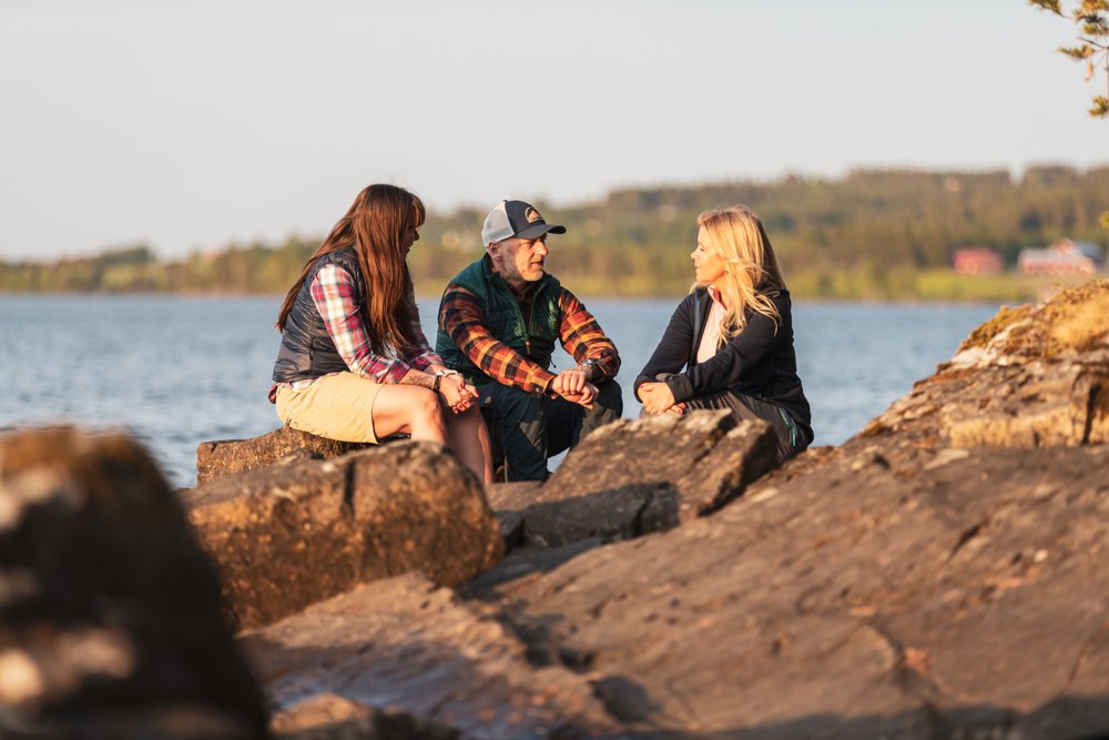 Tre personer sitter på en klippa och samtalar