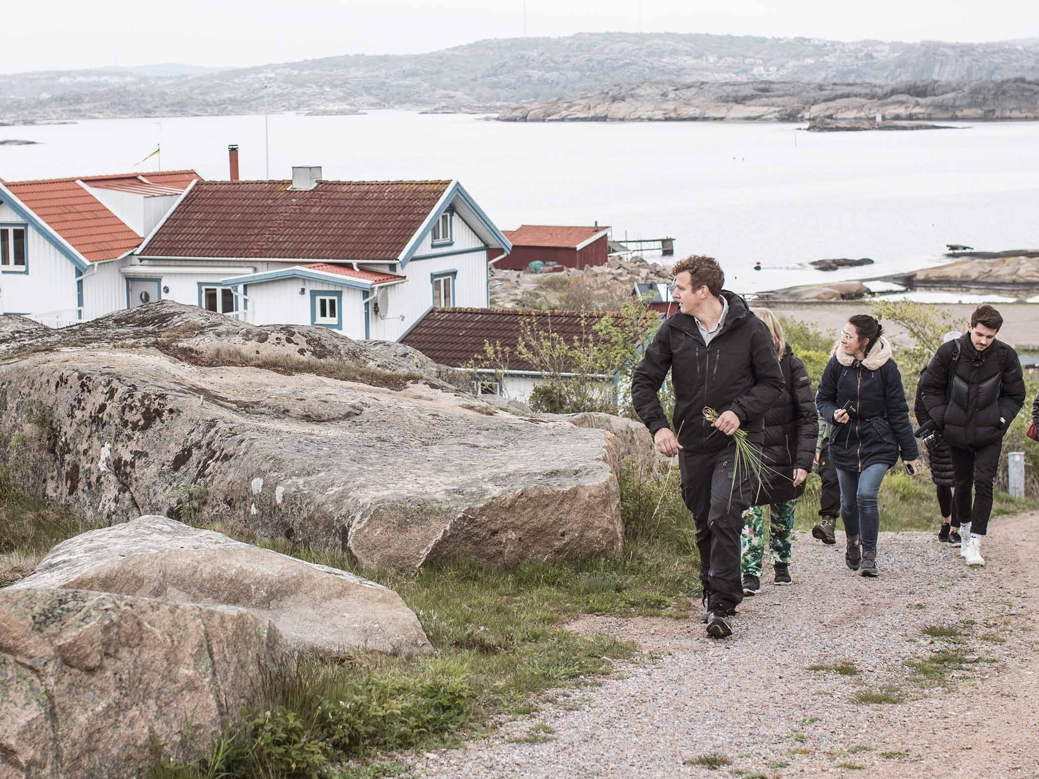 Fler personer går på en stig i ett kustsamhälle.