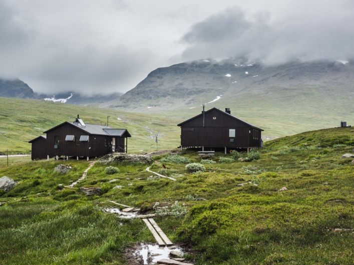 Viterskalet fjällstuga i blött och dimmigt väder.