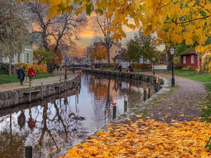 Höstpromenad längs en kanal kantad av färggranna löv som speglas i det stilla vattnet.