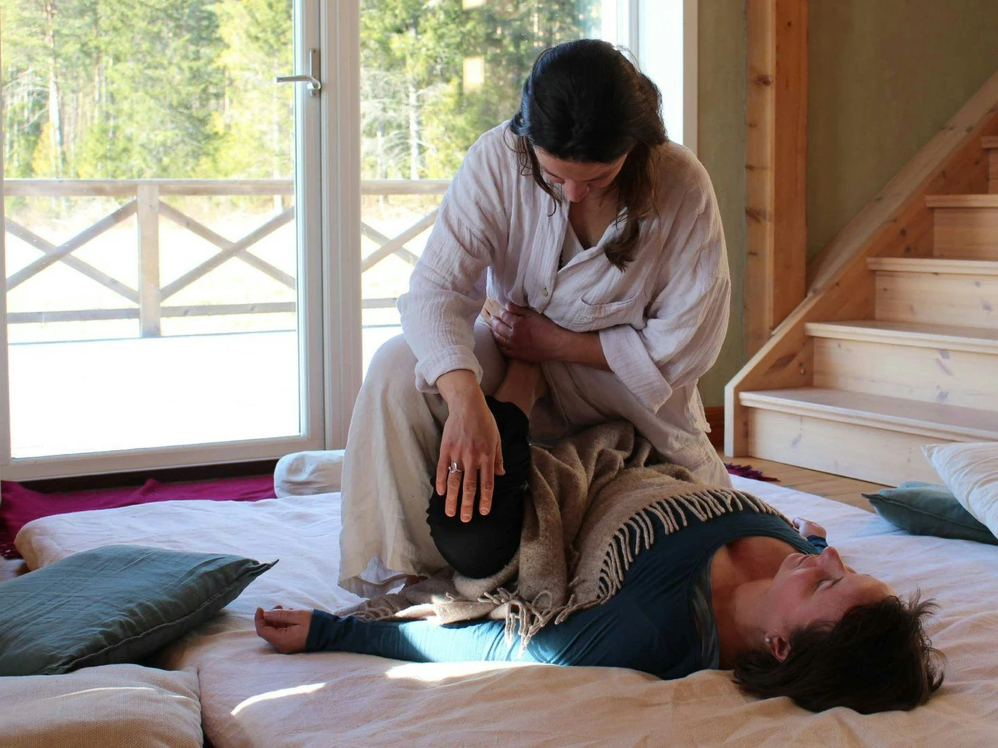 En avslappnande behandling inomhus där en person får massage/stretch på en madrass.