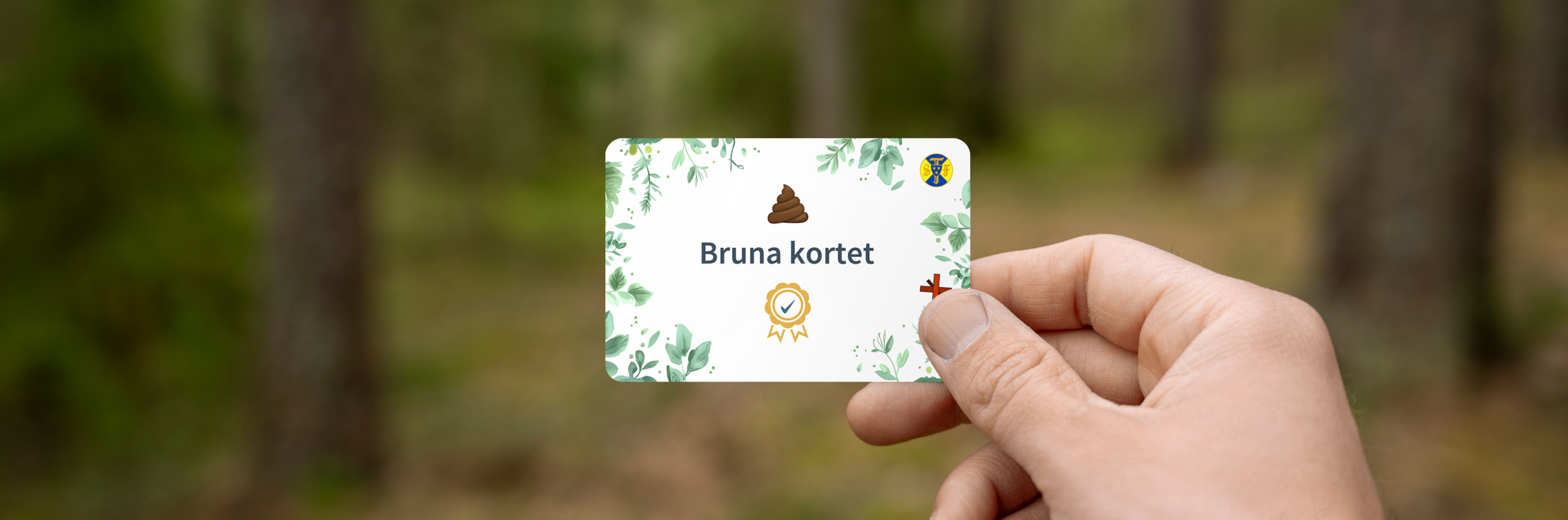 En hand håller upp ett kort med texten Bruna kortet framför en suddig skogsbakgrund.