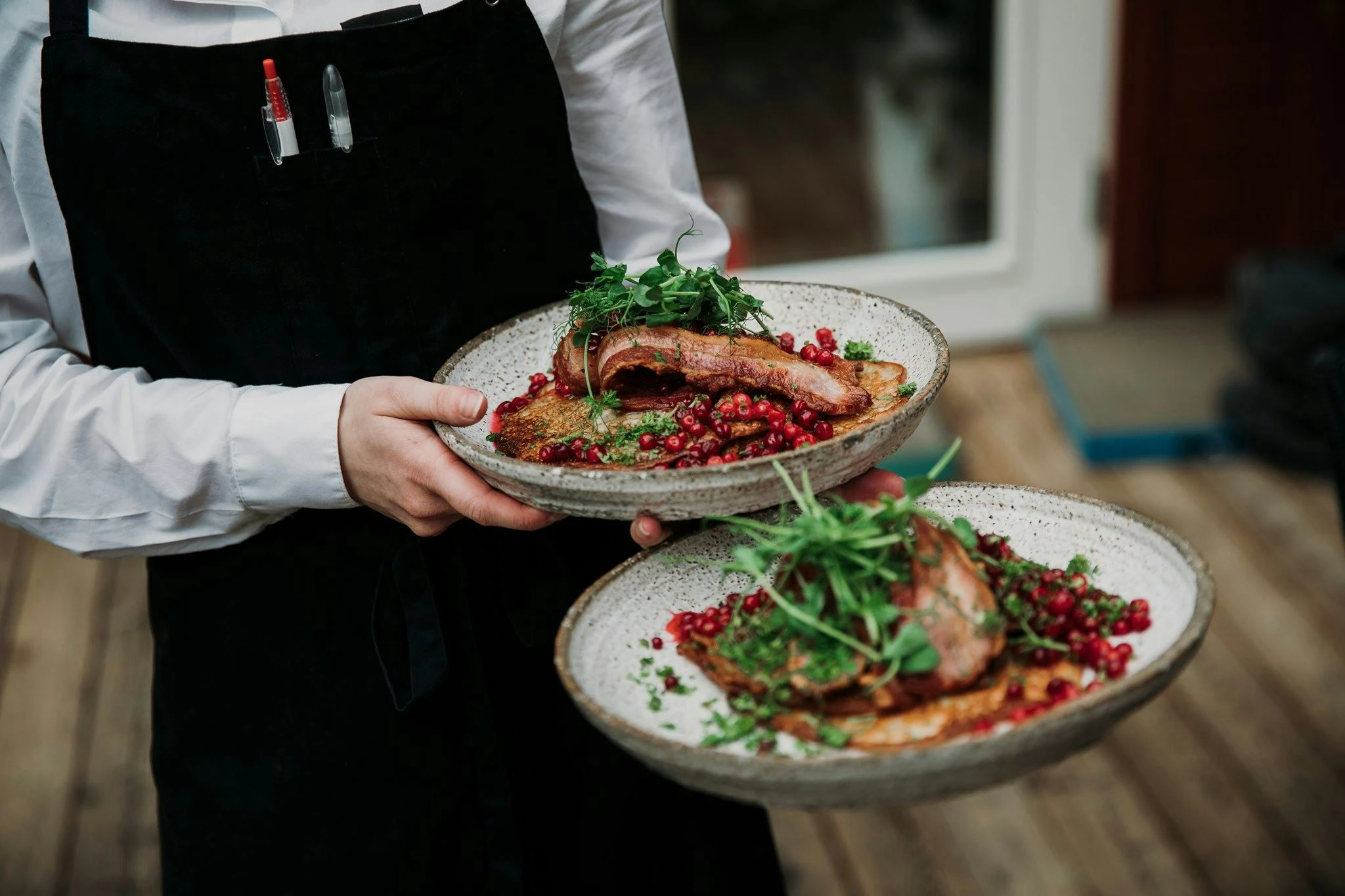 Person som serverar raggmunk med fläsk och lingon.