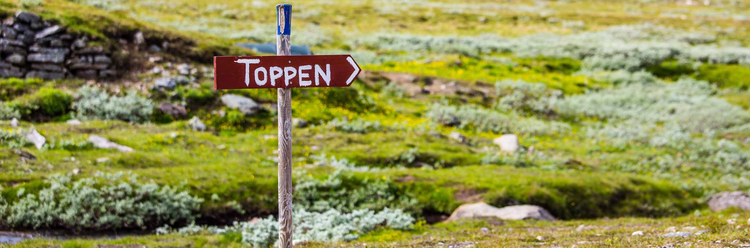 En röd skylt i fjällmiljö som det står 