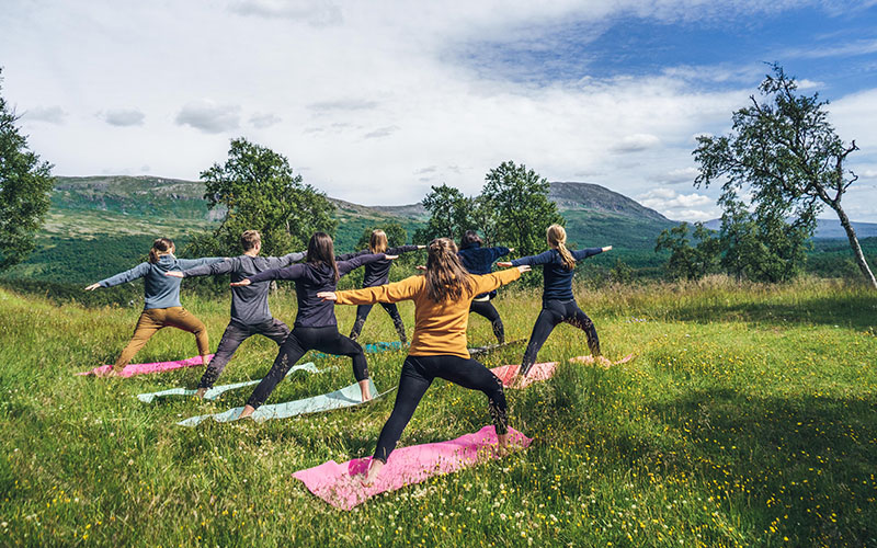 Ett gäng kvinnor yogar tillsammans i fjällmiljö.