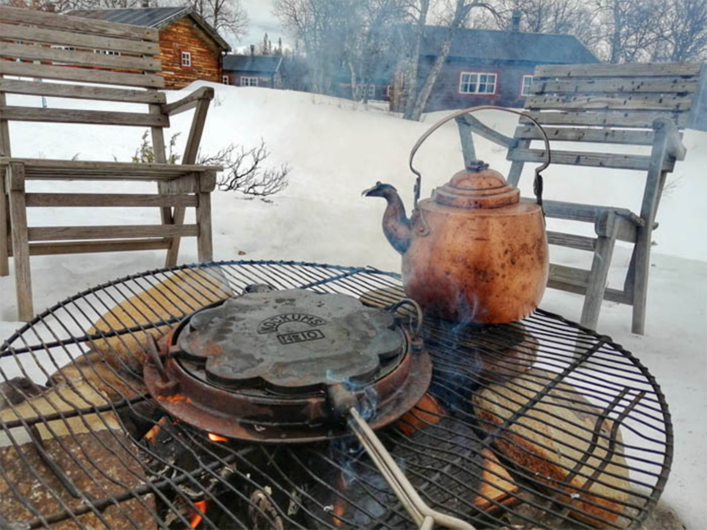 Eldstad utomhus med rökklingande kaffepanna och våffeljärn i snöigt fjällmiljö vid Fjällhornet.