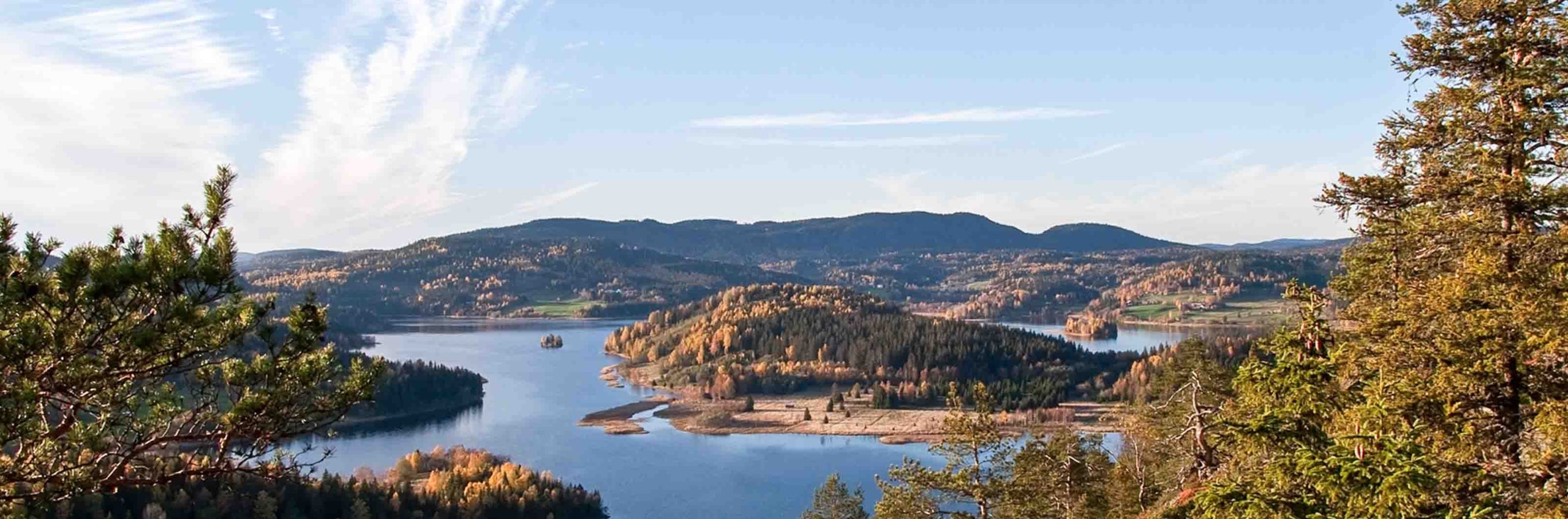 Utsikt över sjö och skogsklädda höjder i höstfärger.