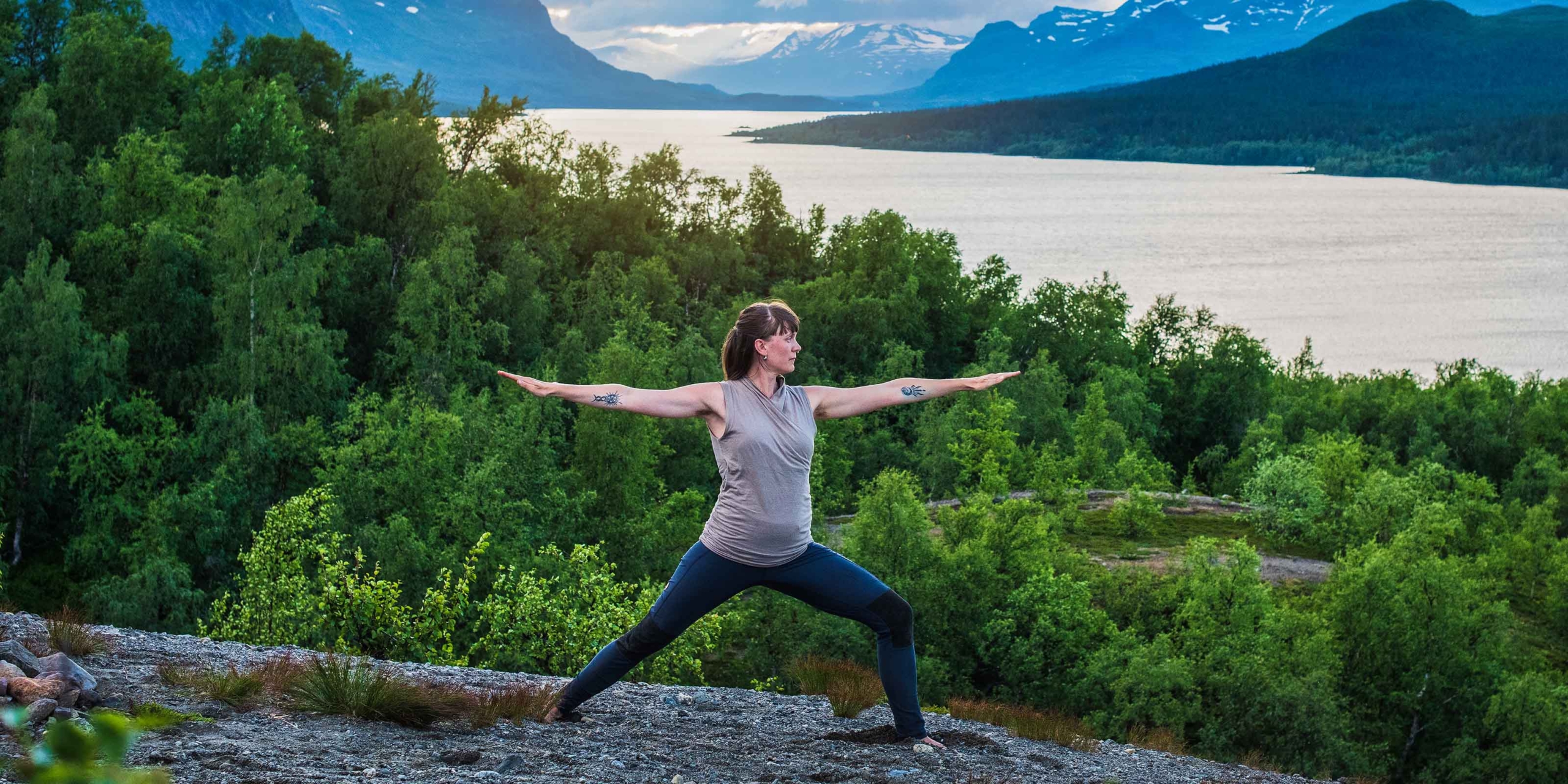 En kvinna yogar på en klippa i Saltoluokta.