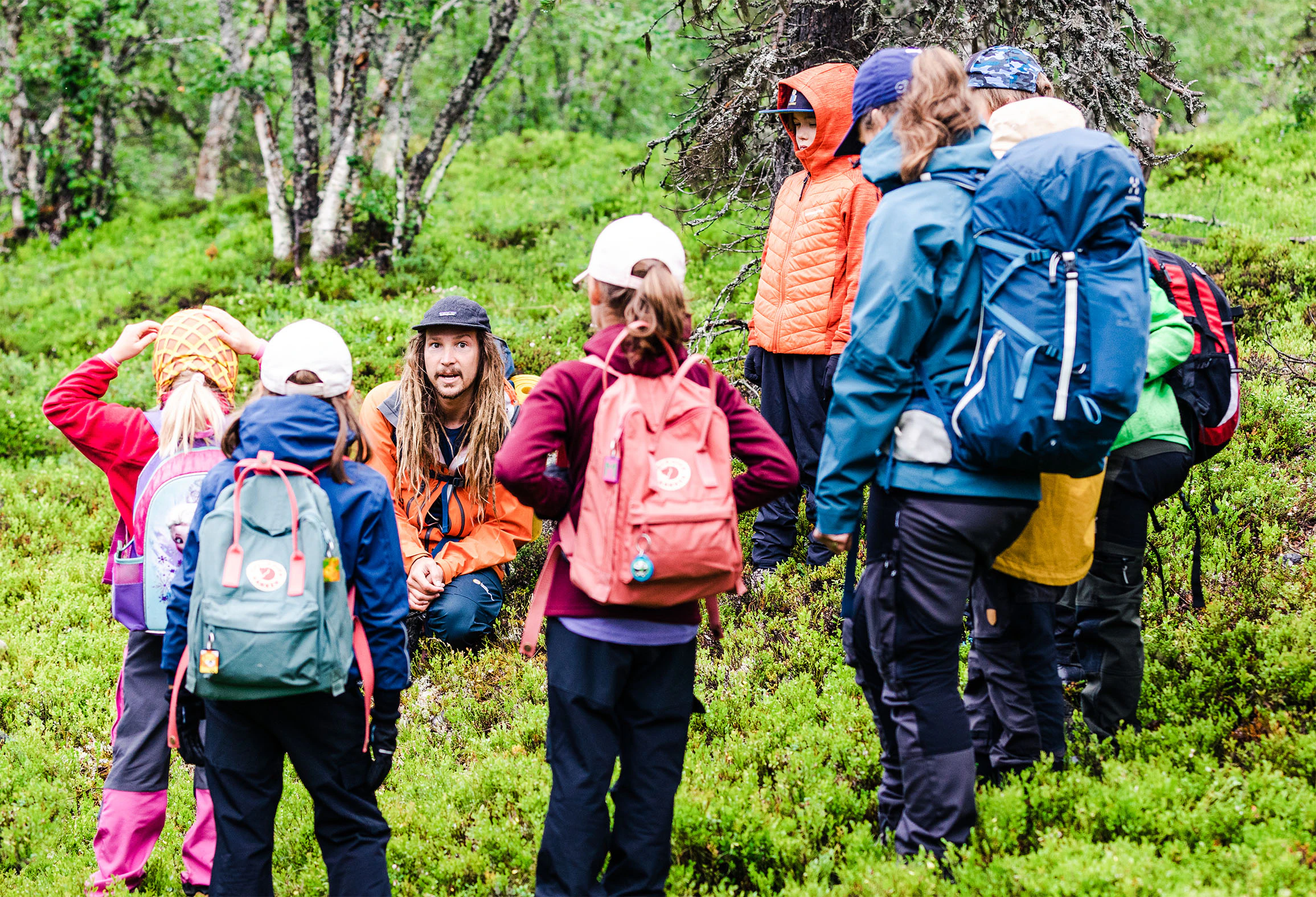 En grupp vandrare med ryggsäckar står samlade i en grön skog.