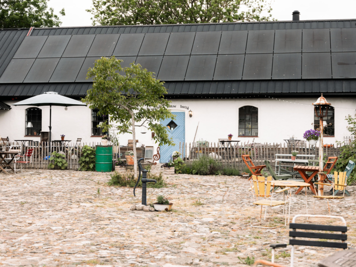 Gårdsmiljö med sittplatser utanför vit byggnad.