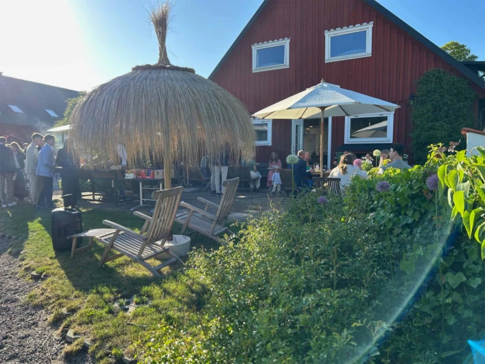 En grupp människor i trädgården på Halmstad Gårdshotell.