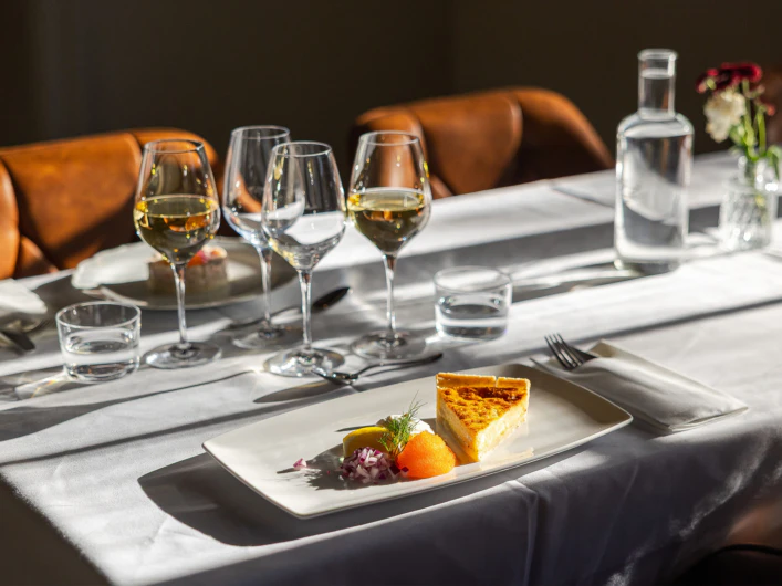 Dukat bord med vinglas och en tallrik med paj, löjrom och tillbehör i varmt ljus.