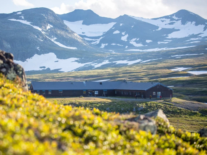 STF Sylarna fjällstation med fjäll och snöfält i bakgrunden.