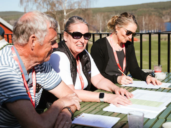 Tre personer sitter utomhus och jobbar på riksstämman.