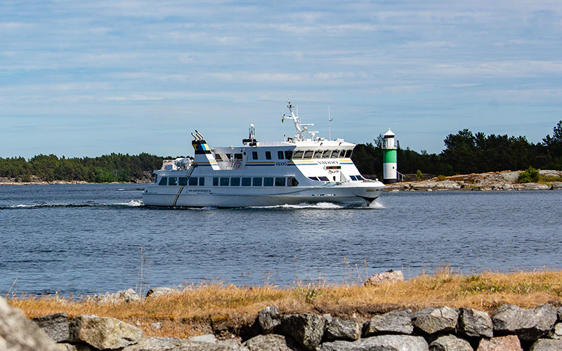 Passagerarbåt från Waxholmsbolaget passerar en fyr i Stockholms skärgård.
