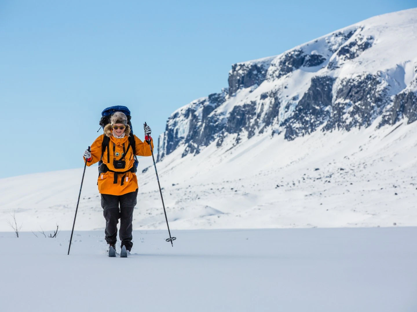 Turskidåkare i orange jacka som skidar på fjället.