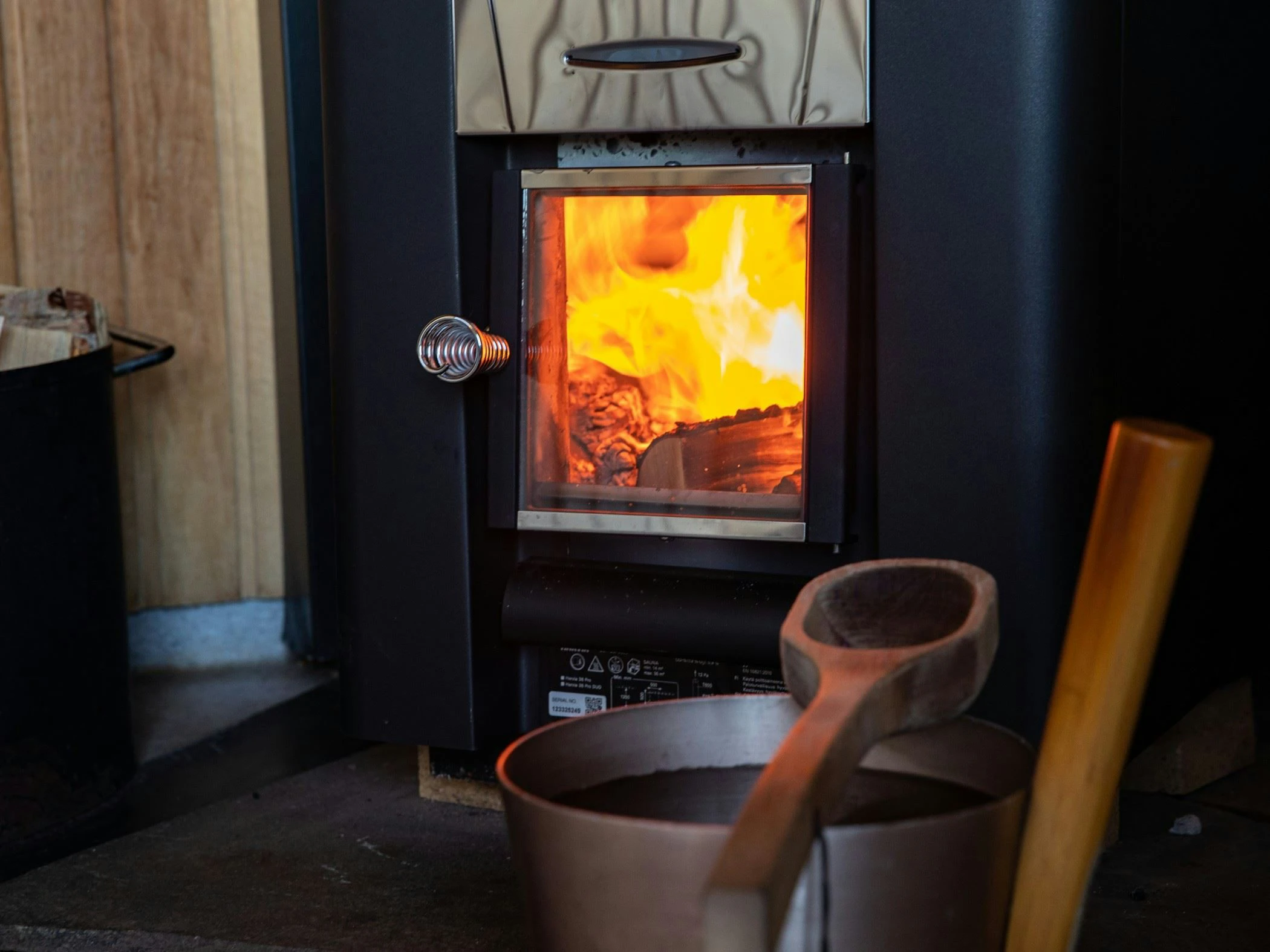 Vedeldad brasa med vattenhink med skopa framför.