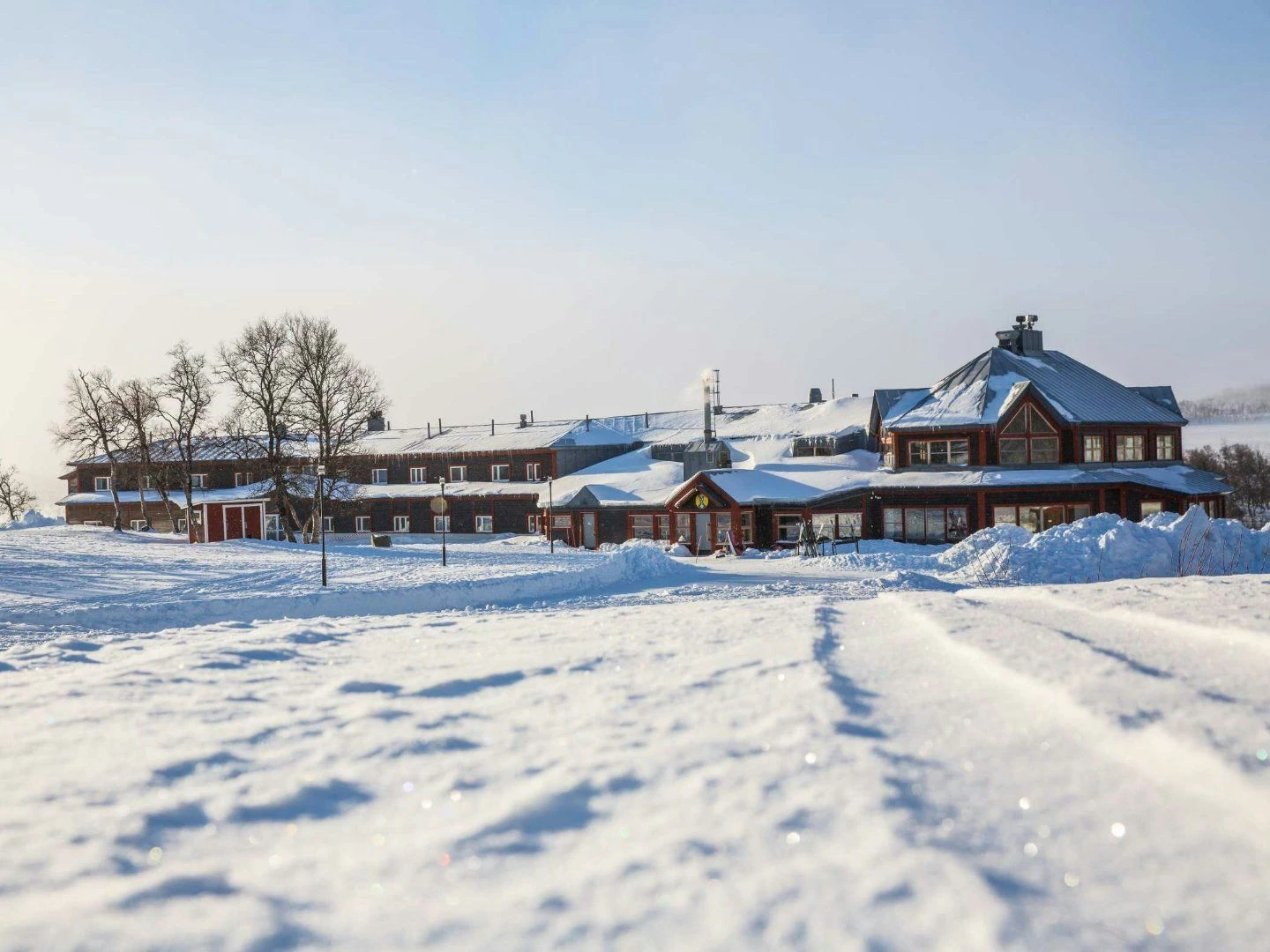 STF Storulvån Fjällstation en solig vinterdag med snötäckt mark framför huvudbyggnaden.