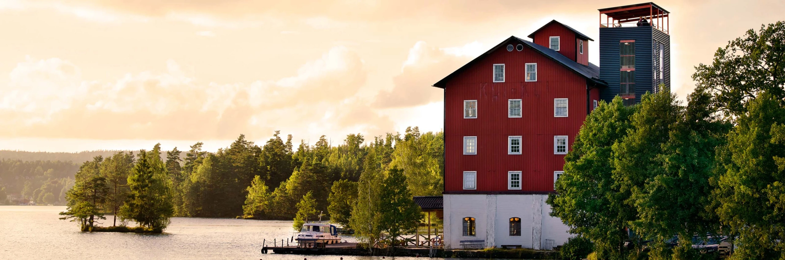 Ett stort rött hus vid vattnet och en brygga.