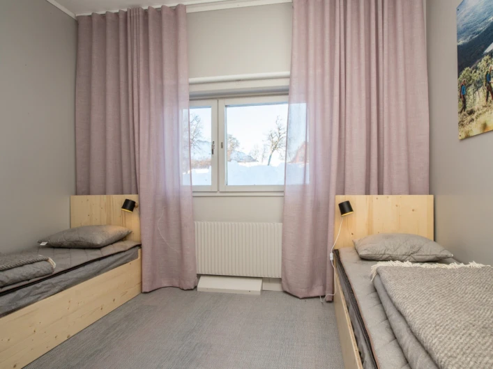 Ett sovrum med två sängar och ett fönster.