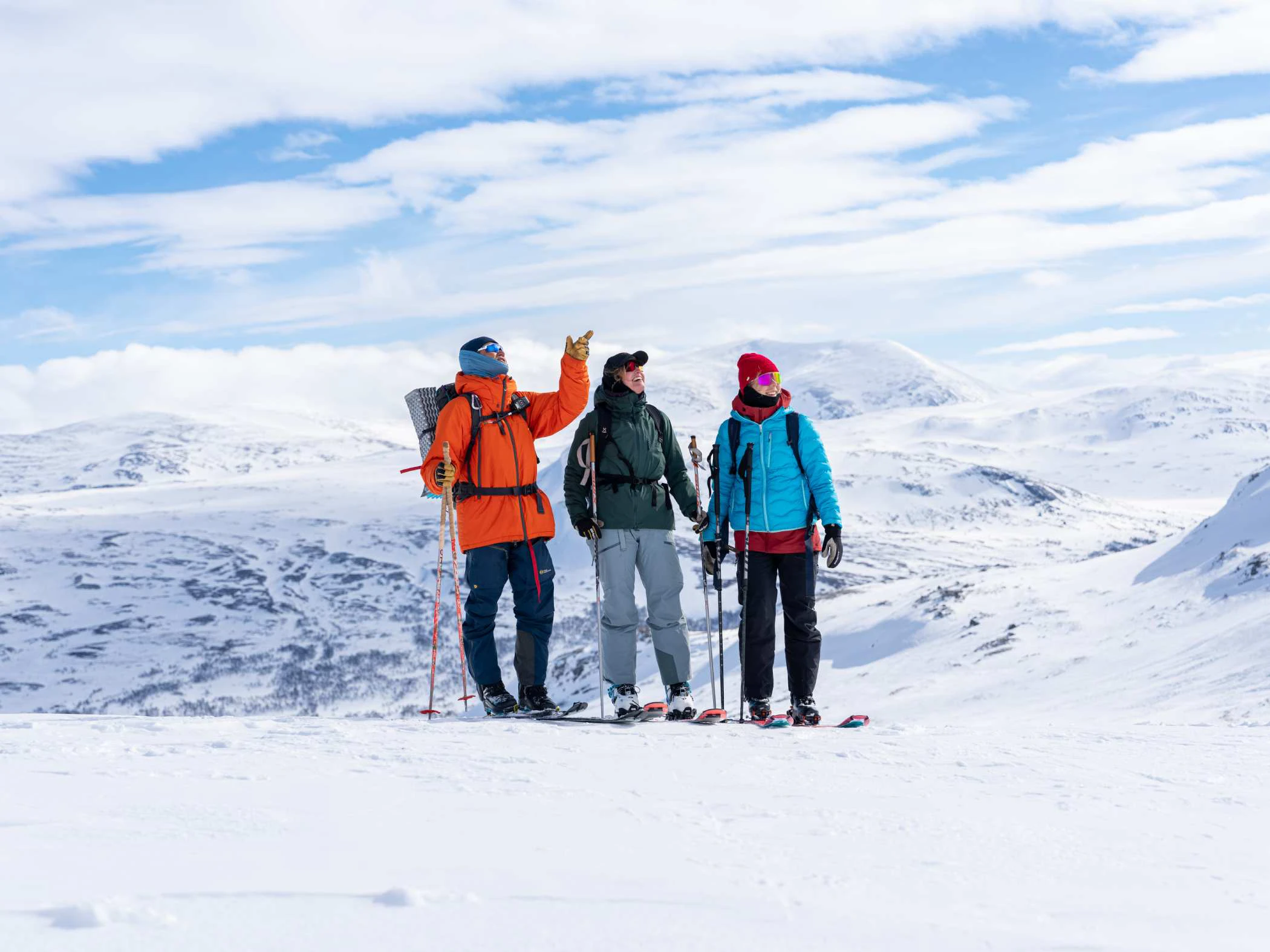 Guide och två deltagare stannar på fjället och blickar ut över det snötäckta landskapet.
