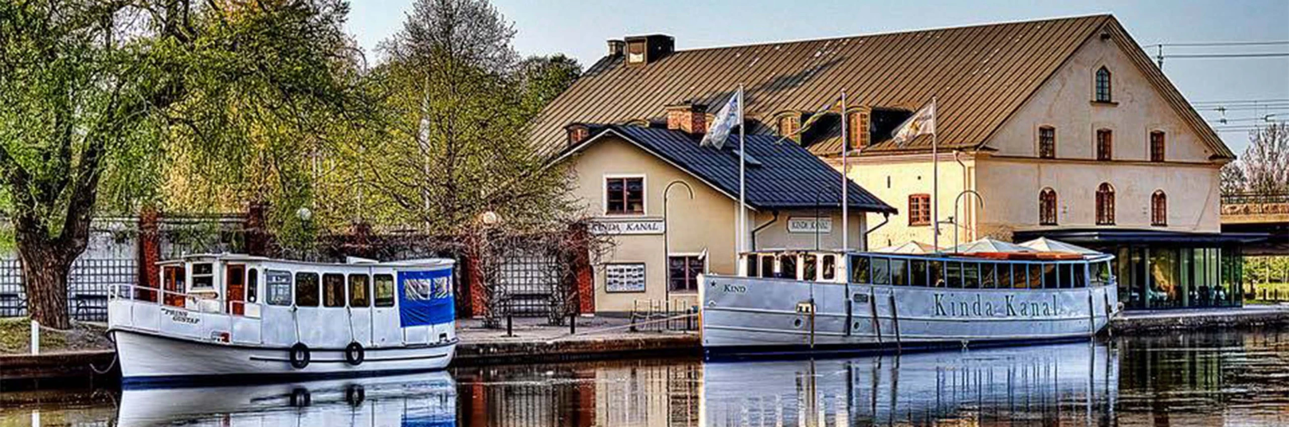 En kanal med båtar och gula hus i bakgrunden.