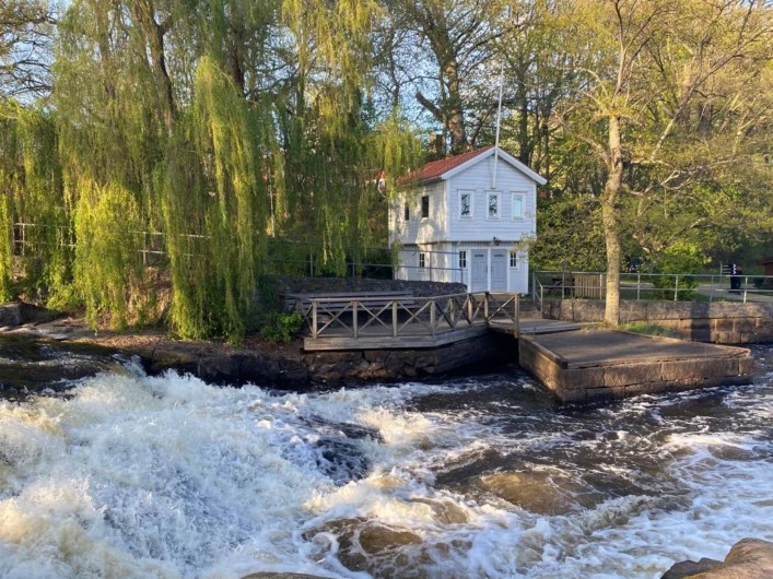 Forsande vatten och slusshus vid Kungsforsen omgivna av grönska.