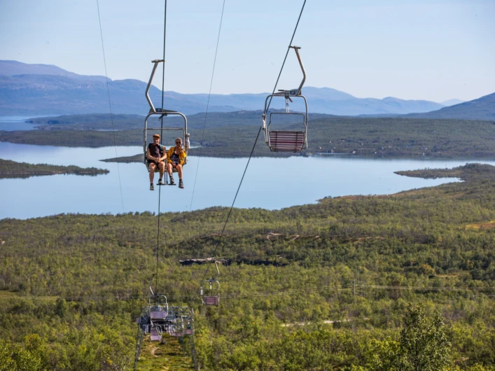 Två personer åker skidlift över en sjö.