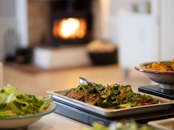 Buffé med grillade grönsaker och sallad framför en sprakande brasa.